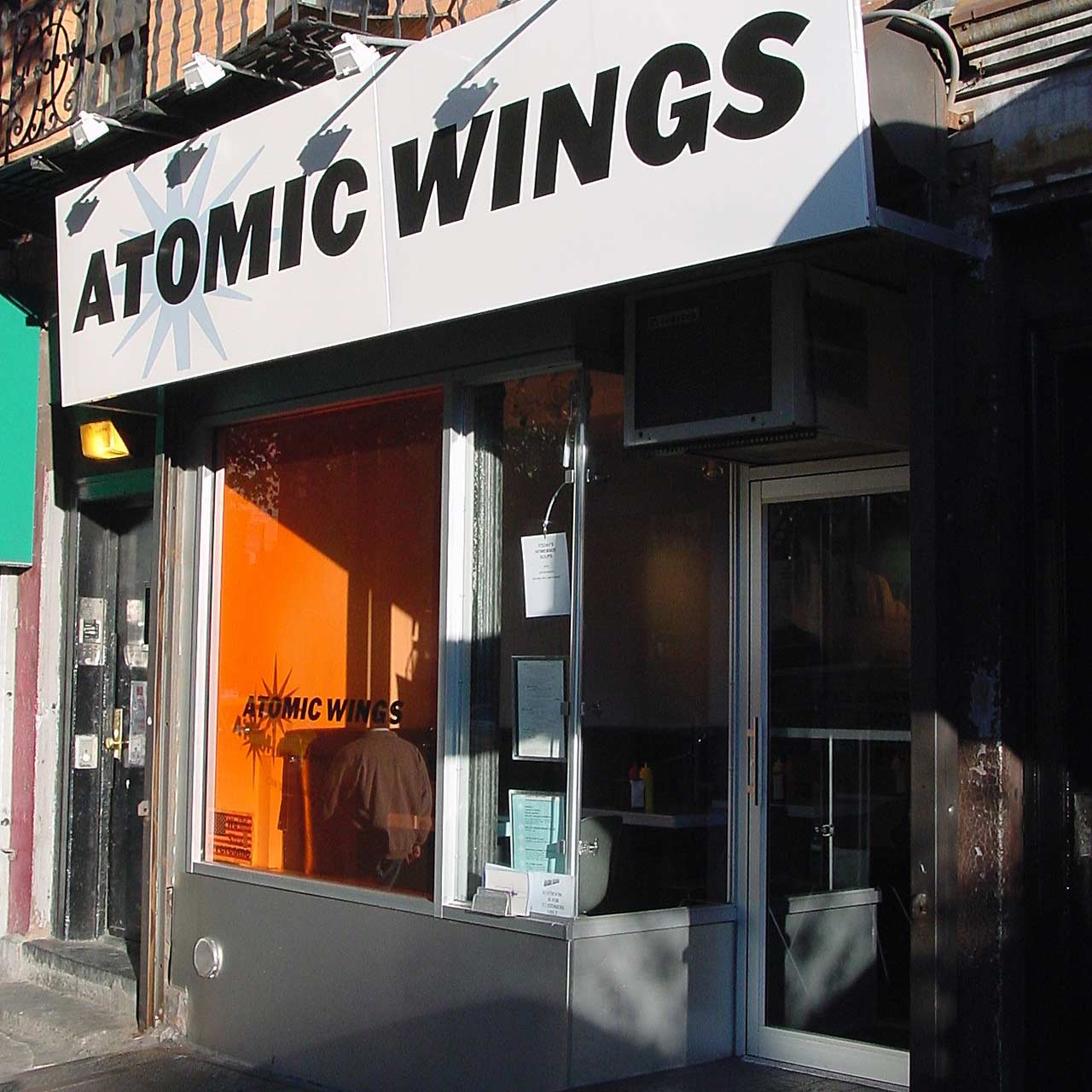 The storefront of Atomic Wings, with a bold sign in white with black letters.