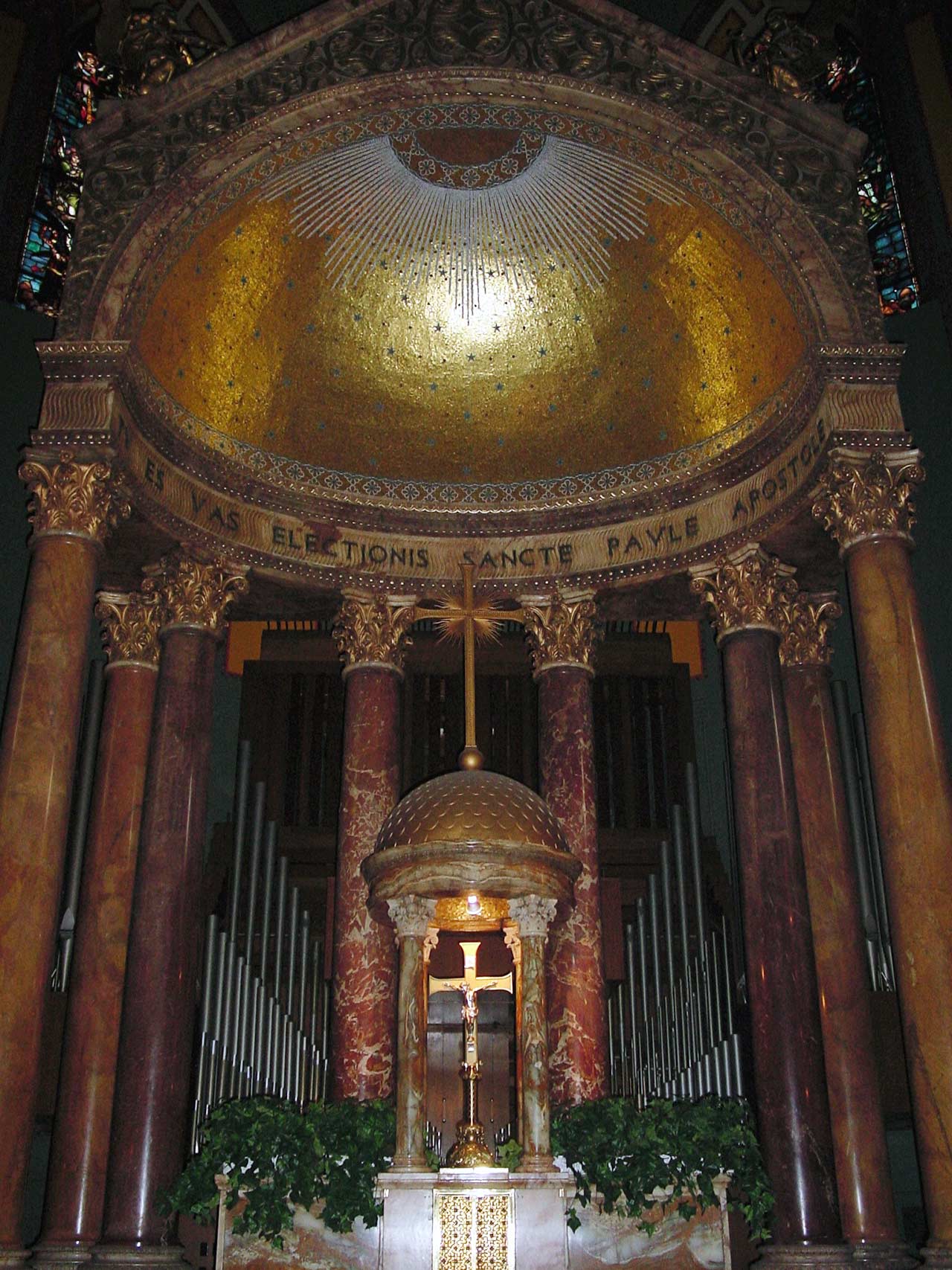 A golden, tiled, starry, half dome above the altar with marble columns supporting the dome.