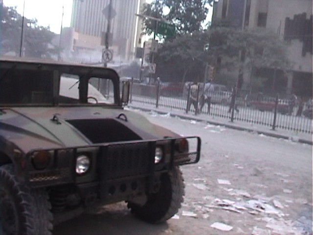A picture of the street covered in dust and office paper, with a military Humvee in the foregraound.