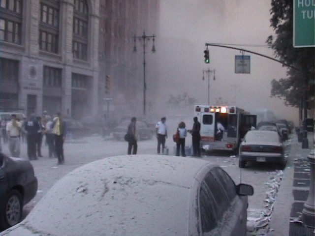 Dust and debris fills the air and settles on the ground and cars on Park Row in Manhattan.
