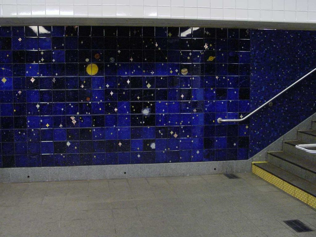 Bottom of a stairwell with dark-blue-tiled walls decorated with stars and planets.