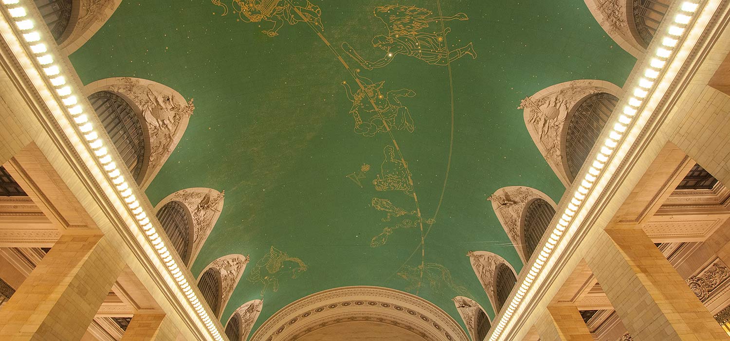 A photo of the green, vaulted ceiling of Grand Central, with illuminated stars and painted constellation figures.