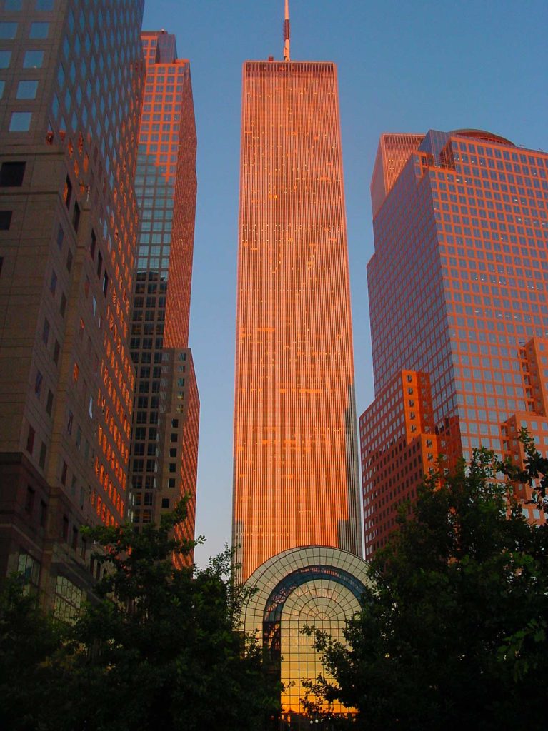 A photo of the North Tower of the World Trade Center at sunset, with orange sunlight shining on the tower and the glassed Wintergarden below.